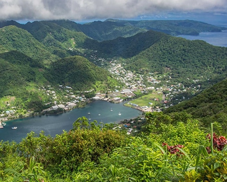 Scenic view of a coastal town surrounded by lush green mountains and a serene bay.